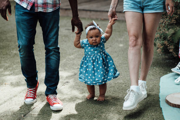 Portrait of candid happy interracial family walking with swarthy baby holding hands at camper park