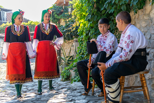 Beautiful young people in traditional Bulgarian costumes, presented doing various activities.