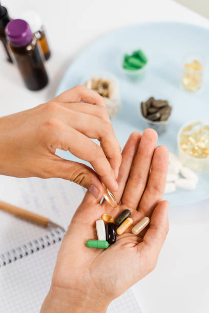 istock Nutritionist is holding different dietary supplement pills in her hands and writing prescription for daily tablets intake for client for health care. 1464570044