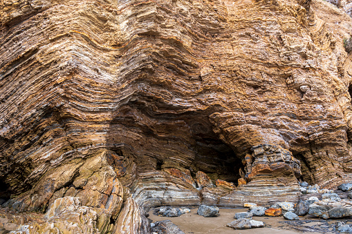 A geological formation on the California coast near Newport Beach illustrating folded rocks caused by years of earth movement and a sea cave caused by the action of waves.