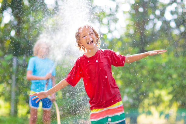 istock Kids play with water sprinkle hose. Summer garden 1464571482