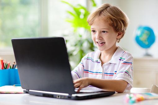 Online remote learning. School kids with computer having video conference chat with teacher and class group. Child studying from home. Homeschooling. Modern gadgets for education. Screen time control.