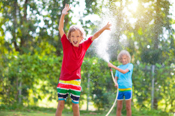 istock Kids play with water sprinkle hose. Summer garden 1464572592
