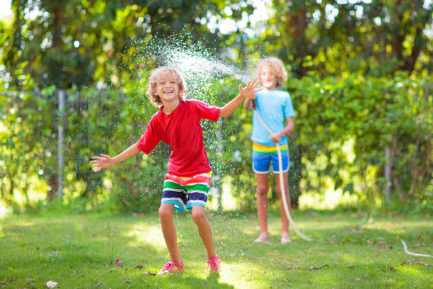 istock Kids play with water sprinkle hose. Summer garden 1464572770
