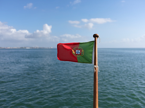 The Portuguese red and green flag on the back of a boat in open waters