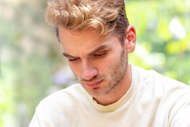 istock Portrait of modern young man looking down, background with copy space 1464574727