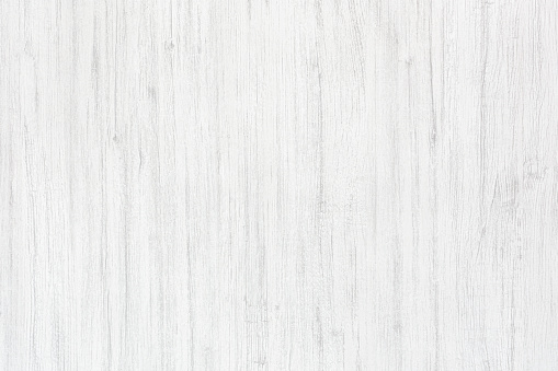 White wood background. Rough white painted old wooden board. A wood grain pattern featuring even grains of wood running vertically across the image. The board has few cracks and knots.
