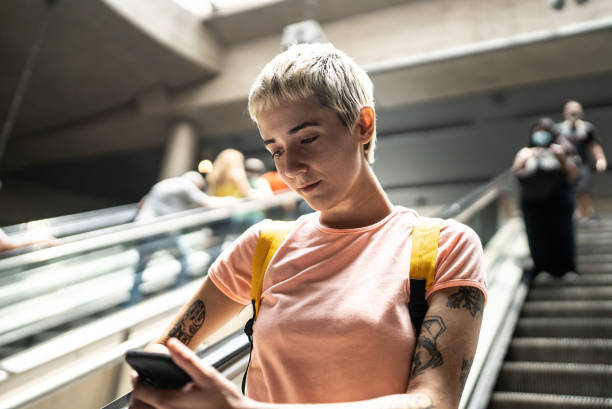 istock Young woman using the mobile phone on the escalator in the subway station 1464578021
