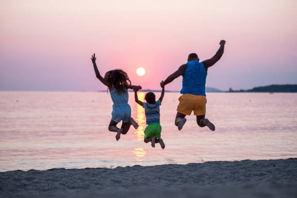 istock dad and kids jumping on the beach 1464578444