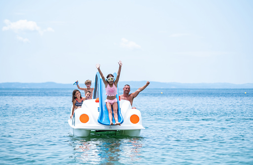 Group of young people with raised hands enjoying in a speedboat ride.   