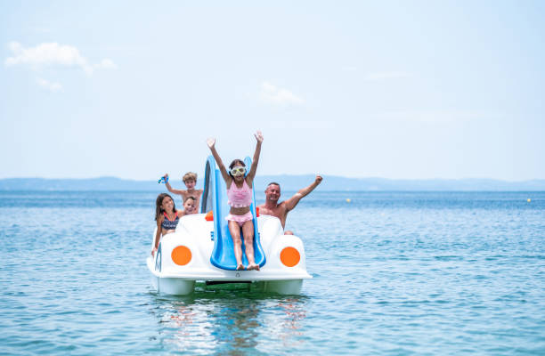 Father and children ride in a pedal boat. Father and children are riding in a pedal boat, they are enjoying themselves and everyone is laughing. pedal boat stock pictures, royalty-free photos & images