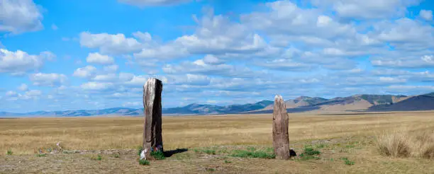 Photo of Two ancient menhirs with ribbons tied stand like guards in the endless steppe. Gates to the Valley of the Kings, Salbyk Steppe, Khakassia, South Siberia, Russia.