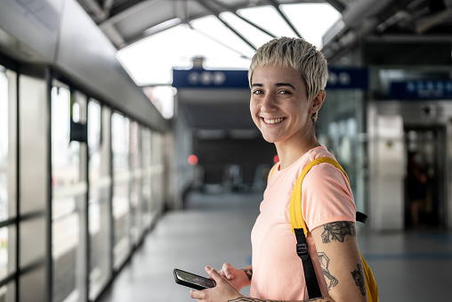 Retrato de una mujer joven usando el teléfono móvil en la estación de metro photo