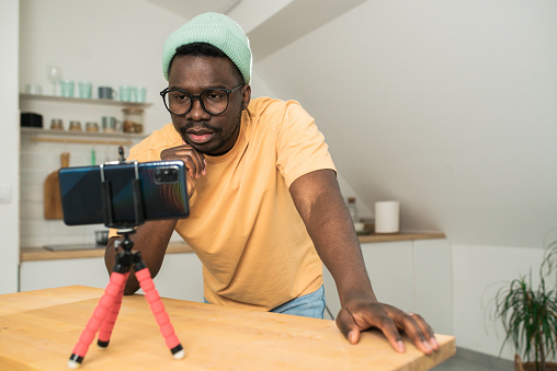Portrait of a young man filming a video blog at his home