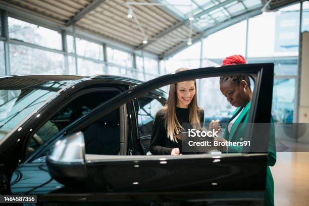 Saleswoman And A Female Customer In A Car Dealership Stock Photo - Download Image Now