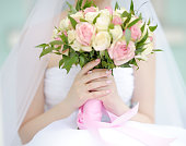 Bride holding wedding flowers roses bouquet, focus on hand and wedding ring