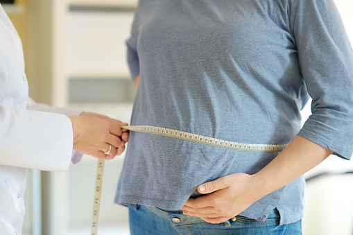 Gynecologist doctor measures with centimeter tape of a pregnant woman. Medical insurance childbearing. Family doctor for gestation. Maternity leave. Health care and medicine.