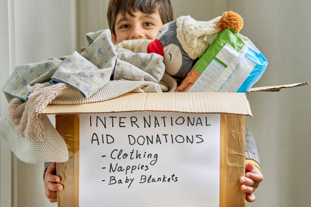glückliches kind, das eine kiste mit humanitärer hilfe für die opfer einer naturkatastrophe unterstützt - child toy giving organization stock-fotos und bilder