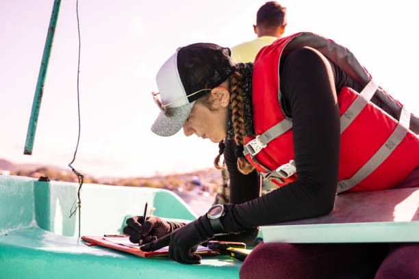 Marine biologist writing data on top of a boat stock photo