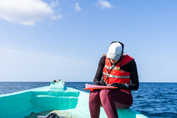 marine biologist writing down data sitting on a boat - 生物學家 個照片及圖片檔