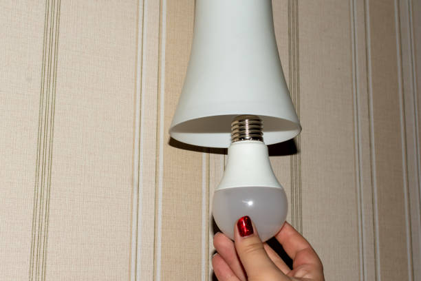 istock Girl screwing in an energy-saving light bulb 1464590318