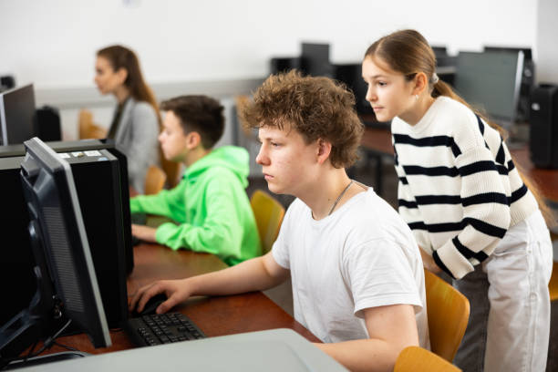 istock Teenage boy helping young girl with PC problem in computer class 1464591149