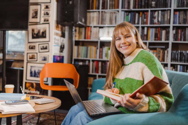 istock Portrait of a female student using laptop in the library and studying 1464592461