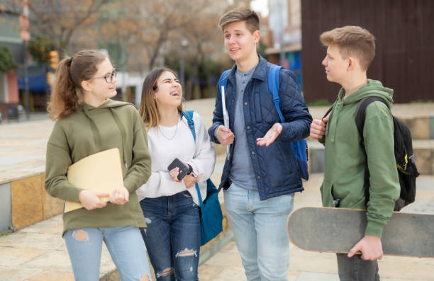 Four teenagers talking about play on walk in street Four teenagers talking about play on walk in the street 12 17 months stock pictures, royalty-free photos & images
