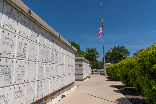 PENSACOLA, FLORIDA - CIRCA JUNE, 2022: Columbariums in Barrancas National Cemetery in Cemetery Road. Columbariums with grave stones at front and view of a half-raised USA flag on the right.
