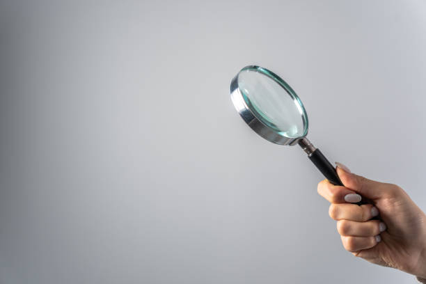 istock Young woman holding magnifying glass 1464597624