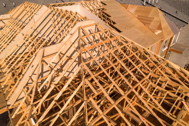 Roofing construction aerial. Wooden roof frame installation of the house. Truss beams structures on new home view from above. Golden hour. House or family home construction and real estate. stock photo