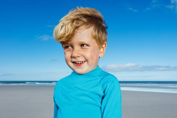 Little funny handsome blond boy pose on the sand ocean beach