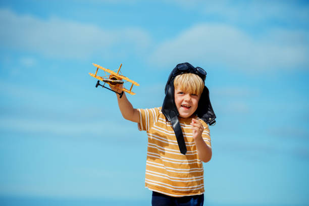 istock Happy blond boy on beach with toy plane model in aviation hat 1464600654