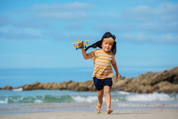 istock Boy run on beach with toy plane model wearing aviation hat 1464600656