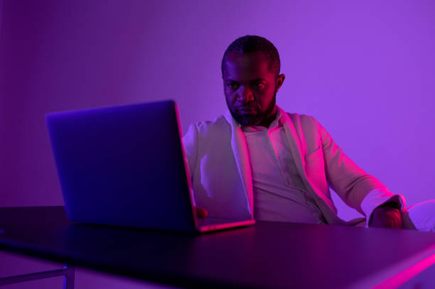 istock a black man in a white suit works at a computer. evening work in the office 1464601212