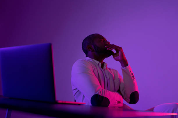istock Photo of pensive man in white suit thinking about new web security project in night office near computer 1464601836