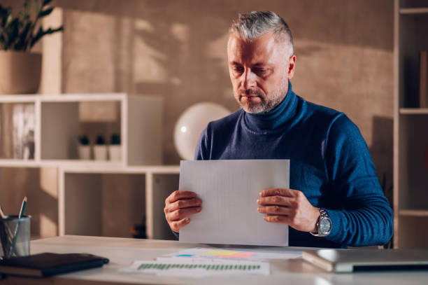 istock Gray haired middle aged man working in a home office 1464602092