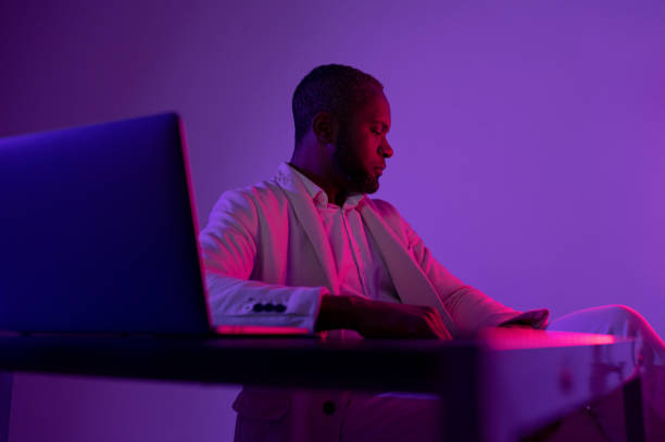 istock black man sitting at the computer in the evening office. IT worker in the evening office 1464602152