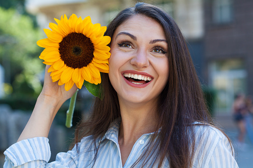 Portrait of a cheerful young woman holding a sunflower