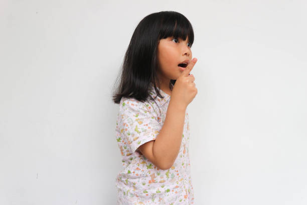 istock Surprised little girl wearing pajama looking at copy space while pointing with hand, isolated on the grey background 1464603519