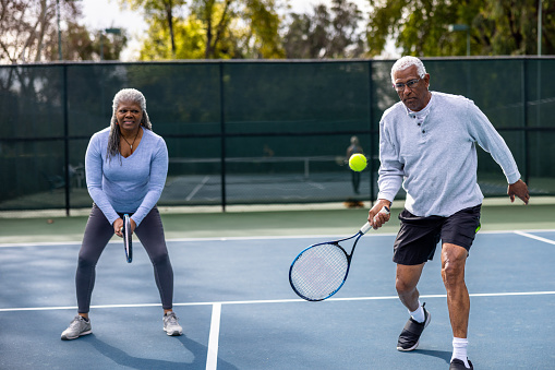 A senior black couple playing tennis together