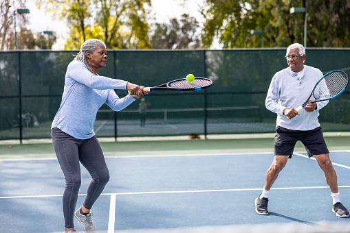 A senior black couple playing tennis together