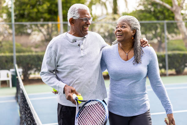 senior pareja negro caminando fuera de la cancha de tenis - tennis couple women men fotografías e imágenes de stock