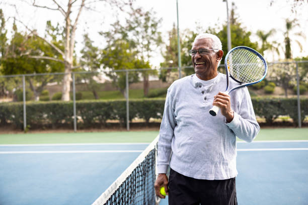 retrato de un hombre negro mayor en la cancha de tenis - senior lifestyle fotografías e imágenes de stock