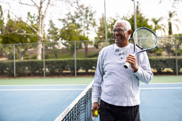 portrait d’un homme noir senior sur le court de tennis - tennis senior adult adult mature adult photos et images de collection