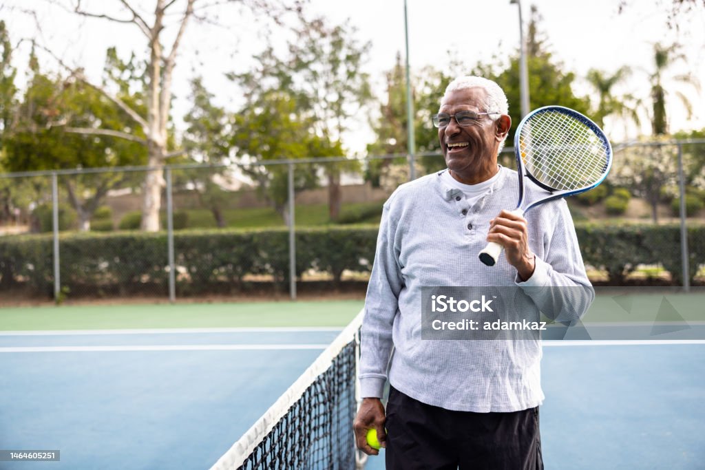Portrait of a senior black man on the tennis court A senior black man smiling Senior Adult Stock Photo