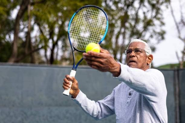 guapo hombre negro mayor jugando tenis - tennis senior adult adult mature adult fotografías e imágenes de stock