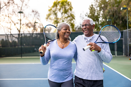 Senior pareja negro caminando fuera de la cancha de tenis photo