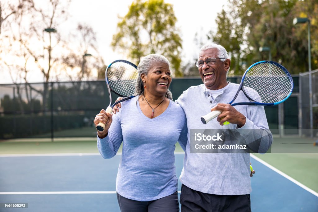 Senior Black Couple Walking Off the Tennis Court A senior black couple leaving the tennis court after their workout. Exercising Stock Photo