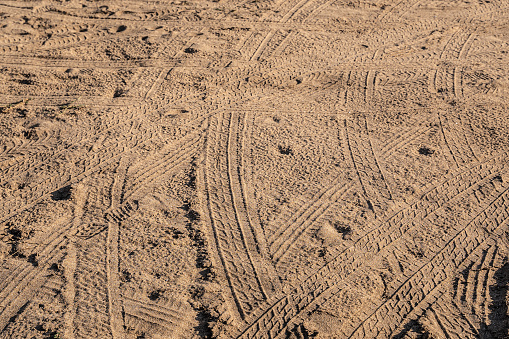 Car tyre imprint in the sand, textured background.